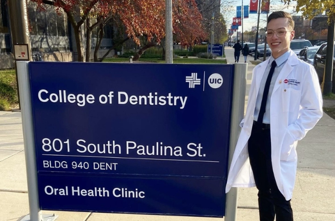 A man smiling by a college of dentistry sign