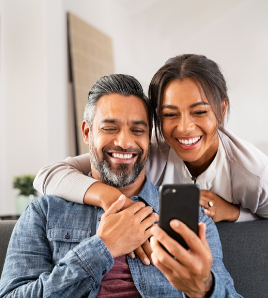 man and woman smiling at phone